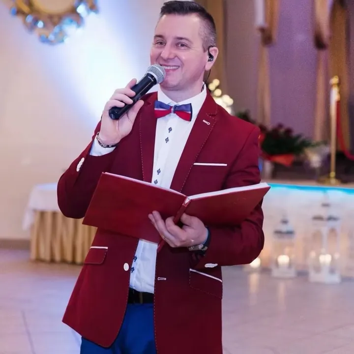 Wodzirej Maxis z mikrofonem i księgą scenariusza